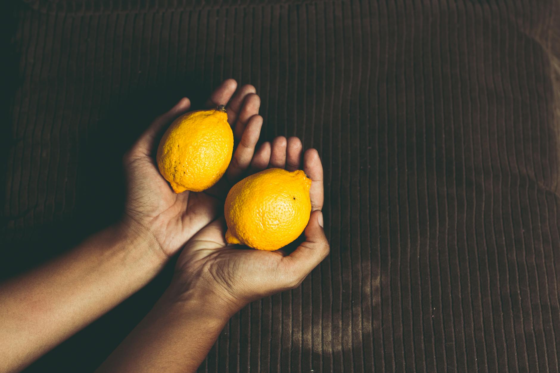 Hand holding an orange vibrator against a purple backdrop, representing modern intimacy and personal pleasure