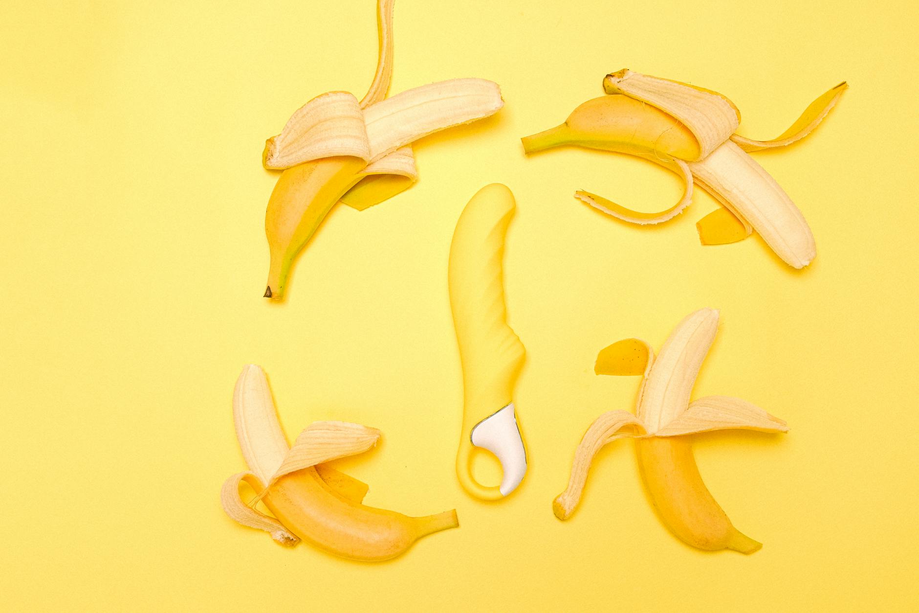 Yellow lemon vibrator surrounded by peeled lemons on a bright yellow background, symbolizing cycle rhythm and pleasure