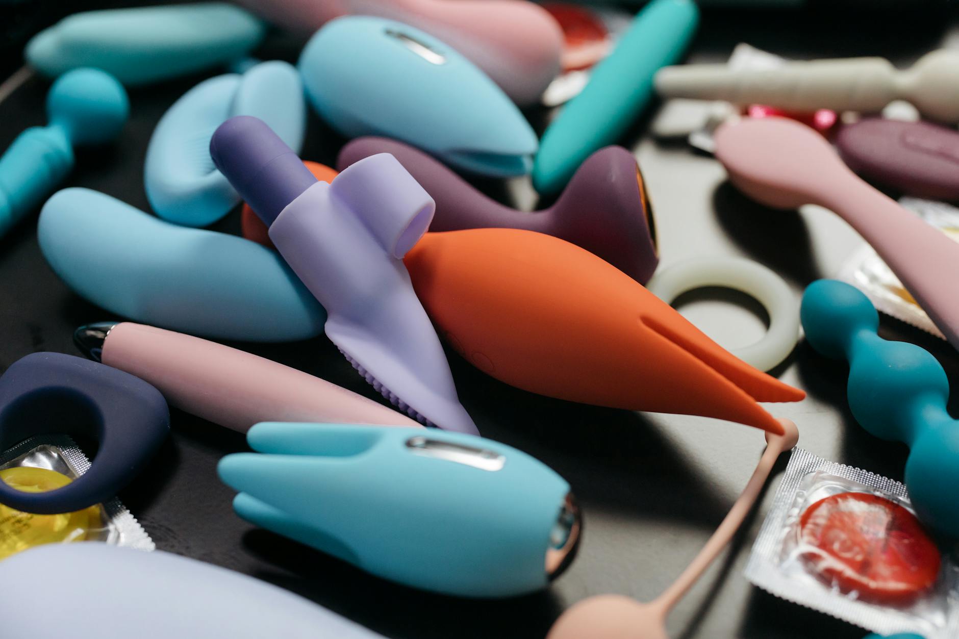 Woman holding a pink vibrator with art books nearby, representing intentional pleasure and intimacy.