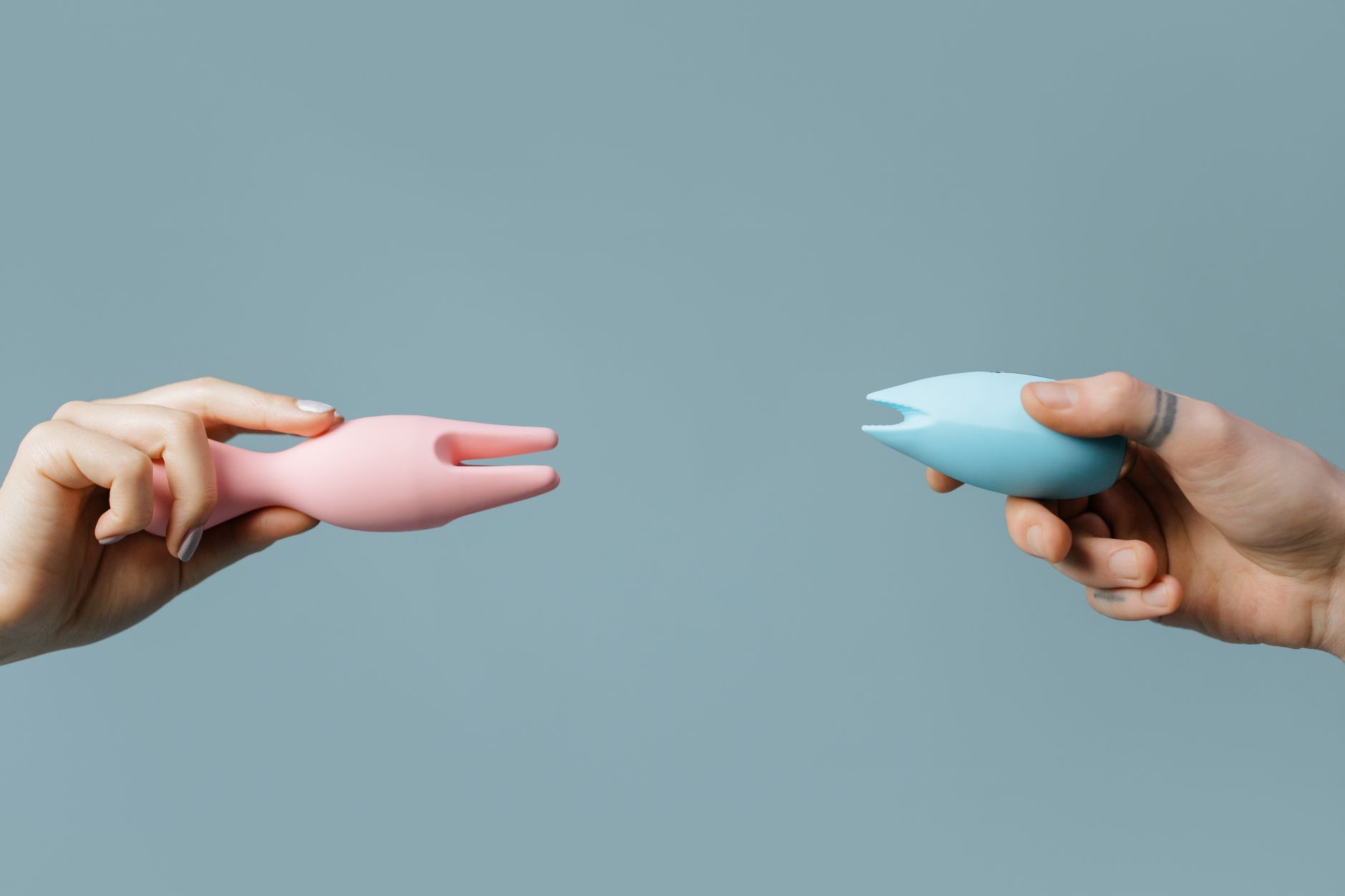 A close-up of a hand holding an orange vibrator against a minimalistic purple backdrop, showcasing modern sensuality.