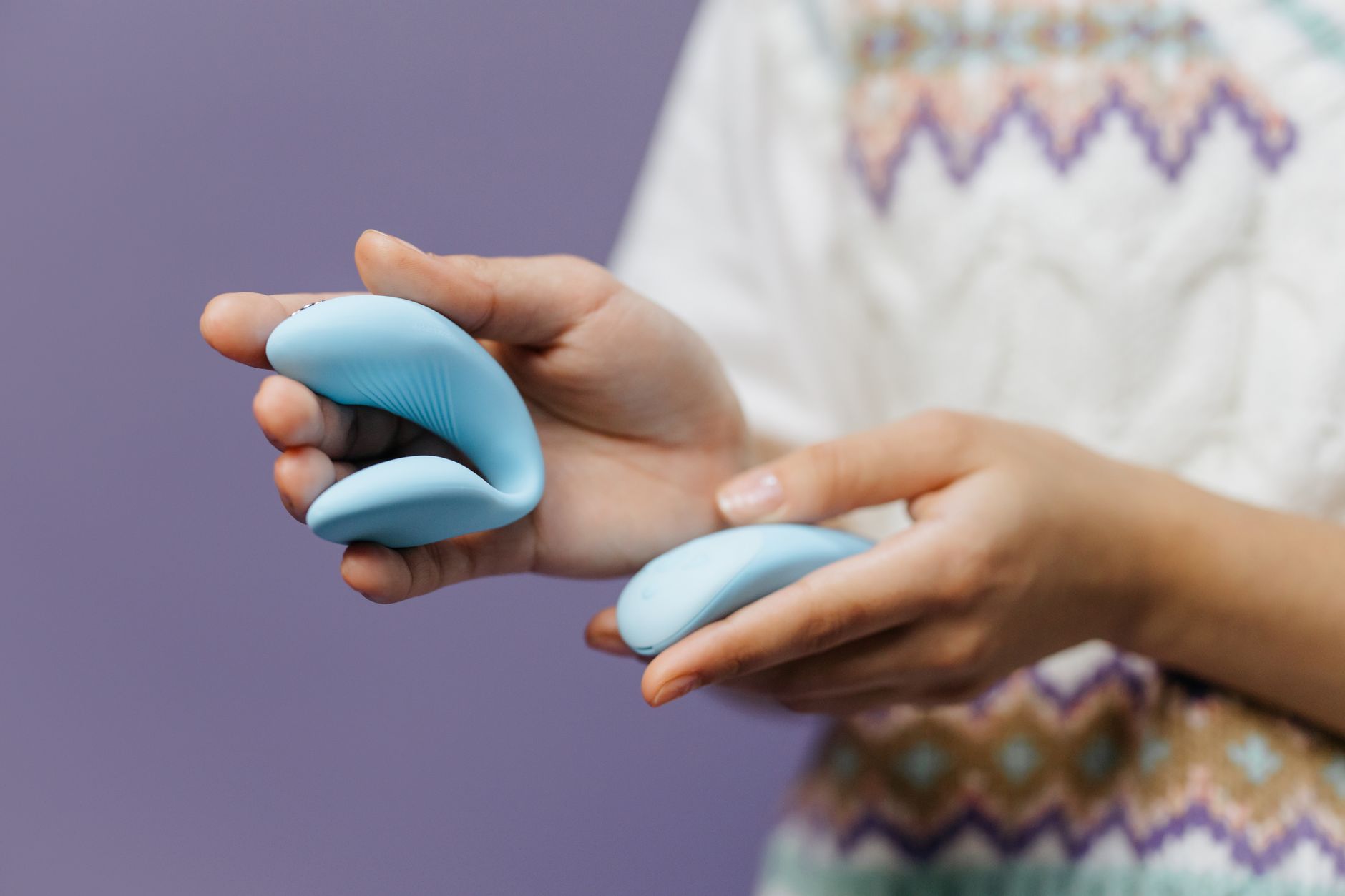 Hands holding a sleek lemon clitoral vibrator against a purple background, symbolizing reconnection and intentional pleasure