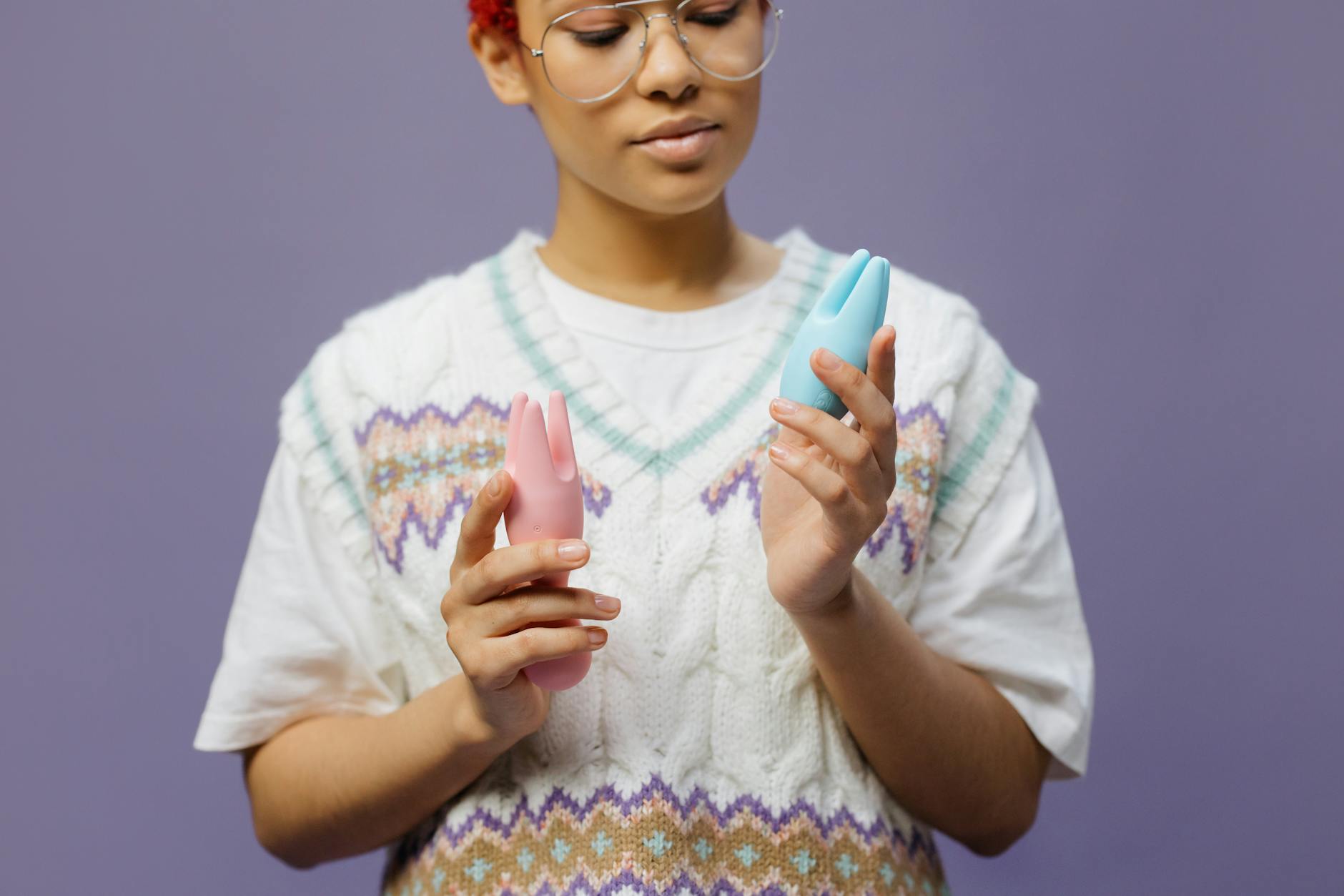 Woman holding blue and pink lemon vibrators while sitting in contemplation
