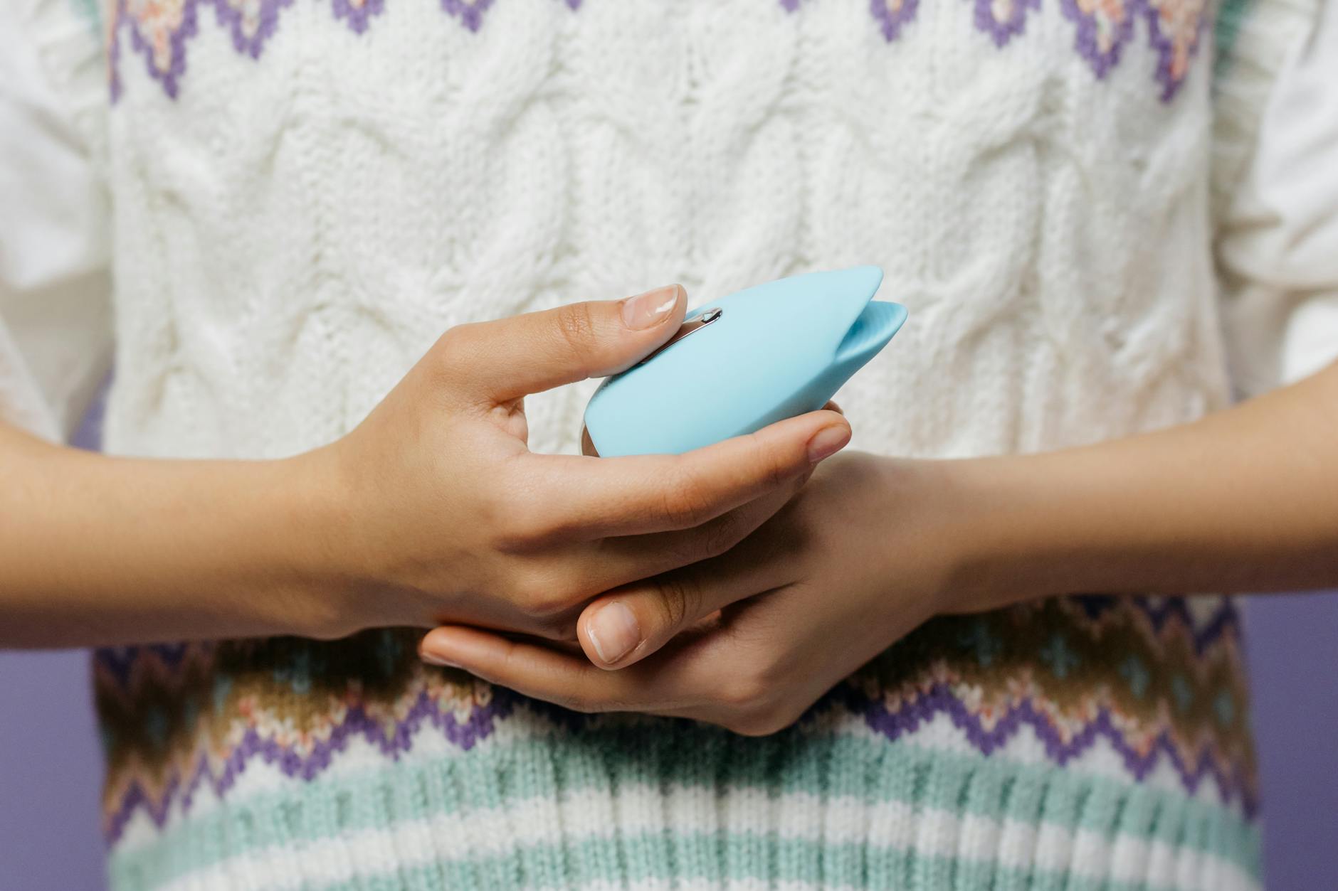 Hands holding a blue lemon clitoral vibrator, showing intimate care and sensitivity